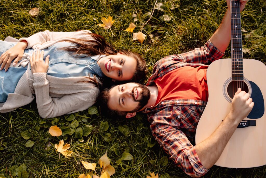 Young couple playing guitar in the grass